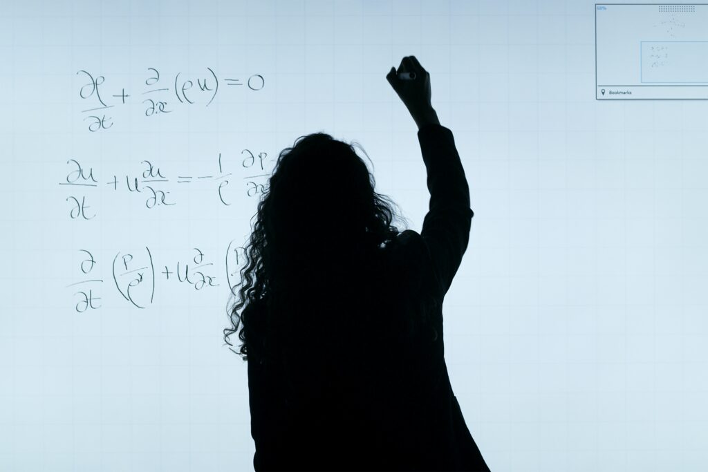 Silhouette of a expert female tutor at our tuition centre, writing maths equations on a whiteboard for an engaging learning experience