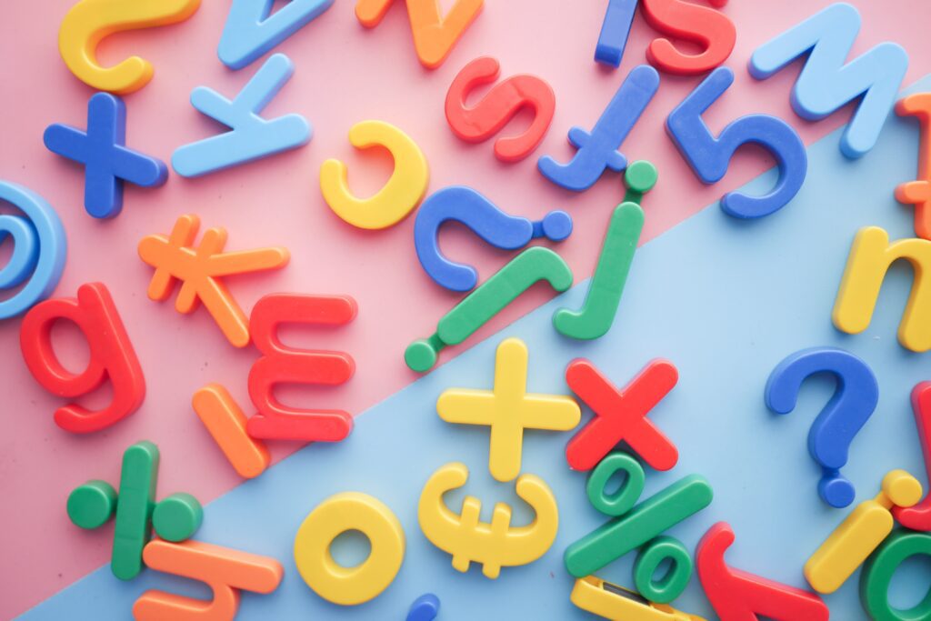 Colourful jumbled letters on a slanted pink and blue background representing the fun and interactive learning approach at our expert tutoring centre